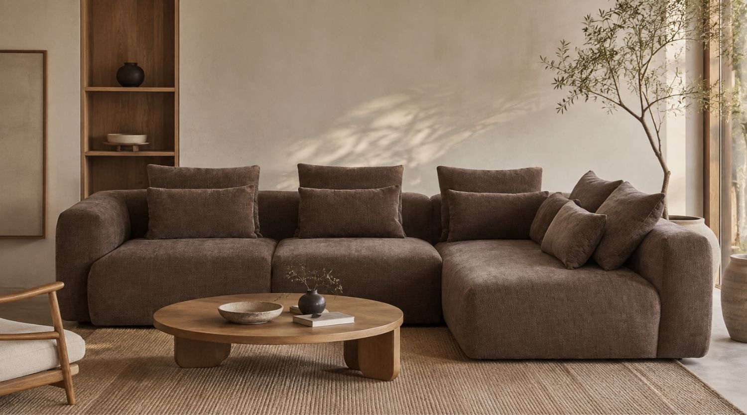 Brown L-shaped sectional sofa in a stylish Japandi living room with neutral decor, a wooden coffee table, and a textured natural rug.