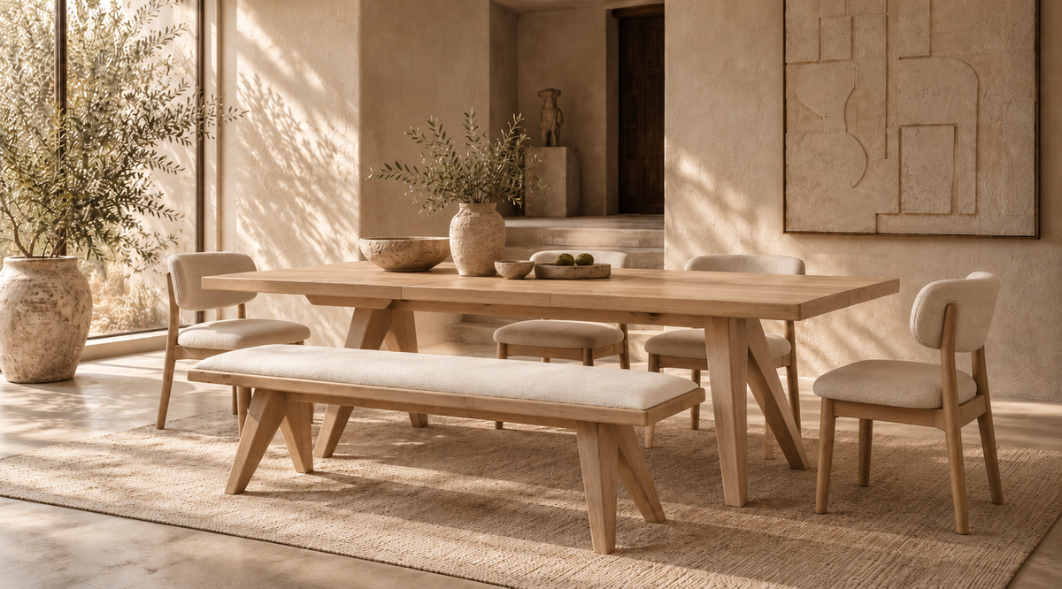Light oak dining table paired with a cream upholstered wooden bench and matching dining chairs in a luxurious Wabi-Sabi dining room featuring textured beige walls, natural sunlight, and minimalist decor.