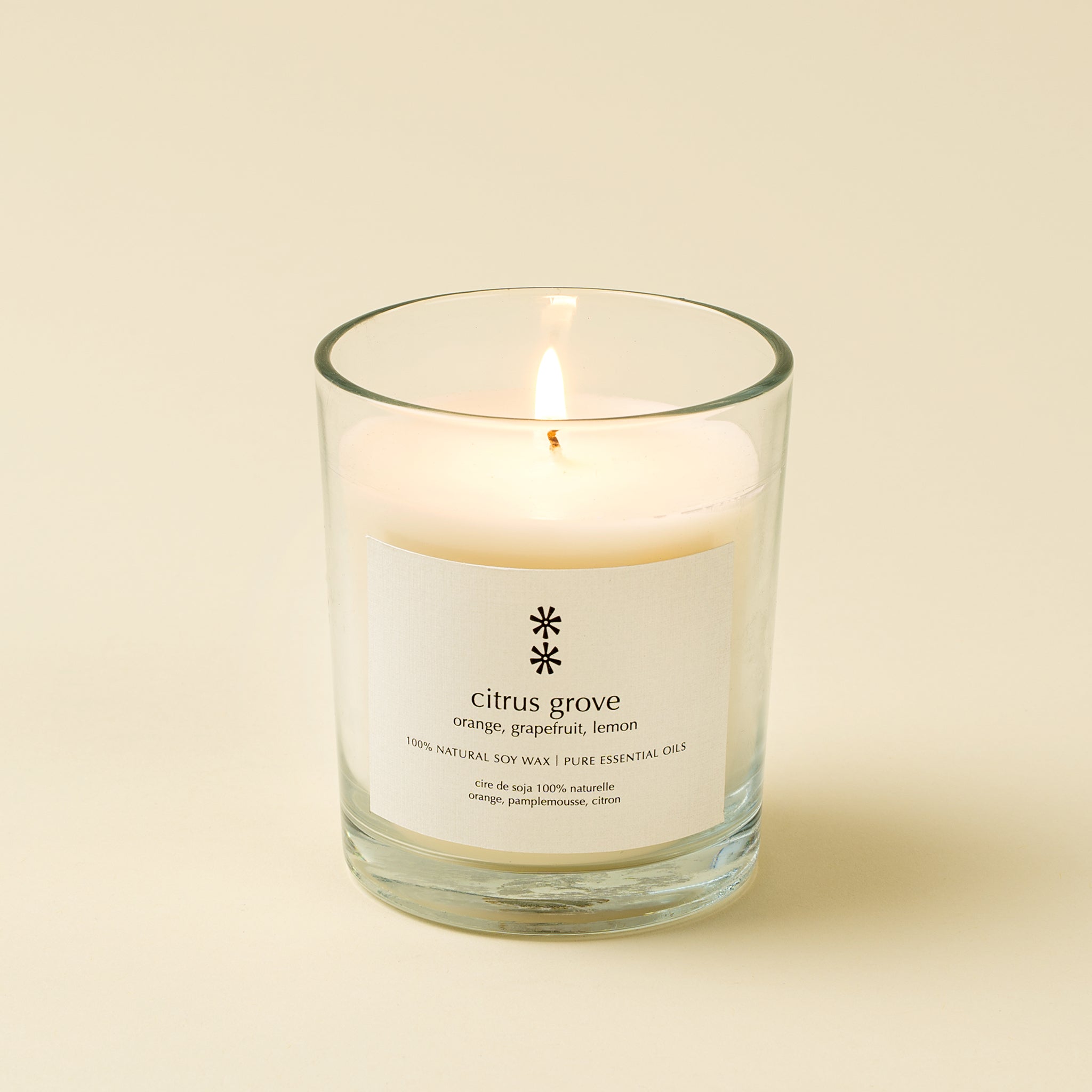 Glass candle with a label on a beige background citrus grove