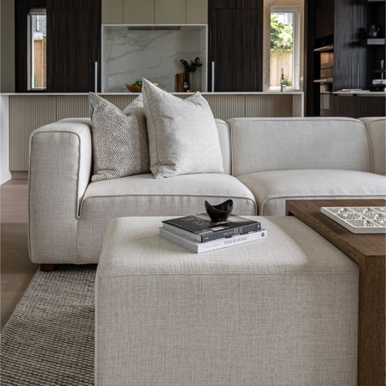Front view of the Forest coffee ottoman featuring a cream upholstered rectangular bench with a nested blonde oak waterfall table