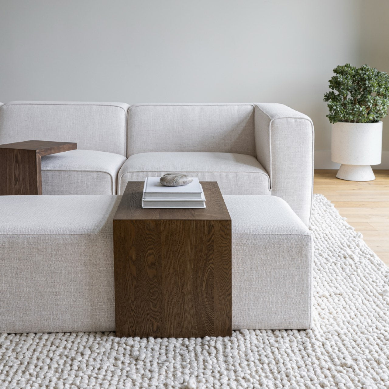 Front view of the Forest coffee ottoman featuring a cream upholstered rectangular bench with a nested blonde oak waterfall table