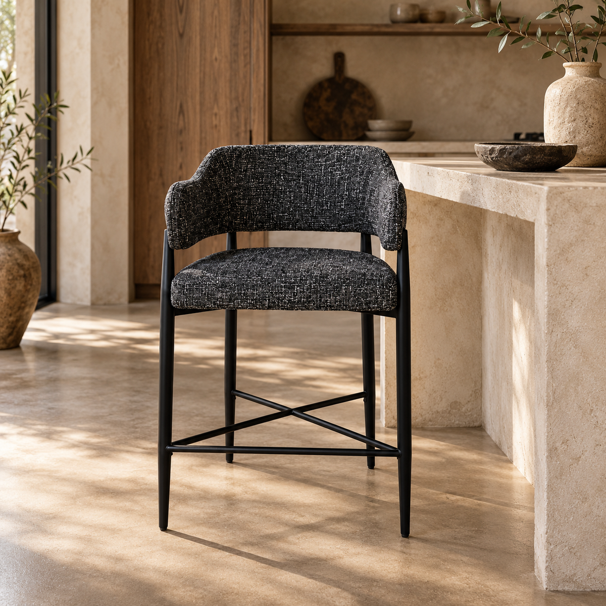 A modern counter-height bar stool with a light beige textured fabric upholstered seat and curved backrest, supported by a slim black metal frame with an X-shaped base.