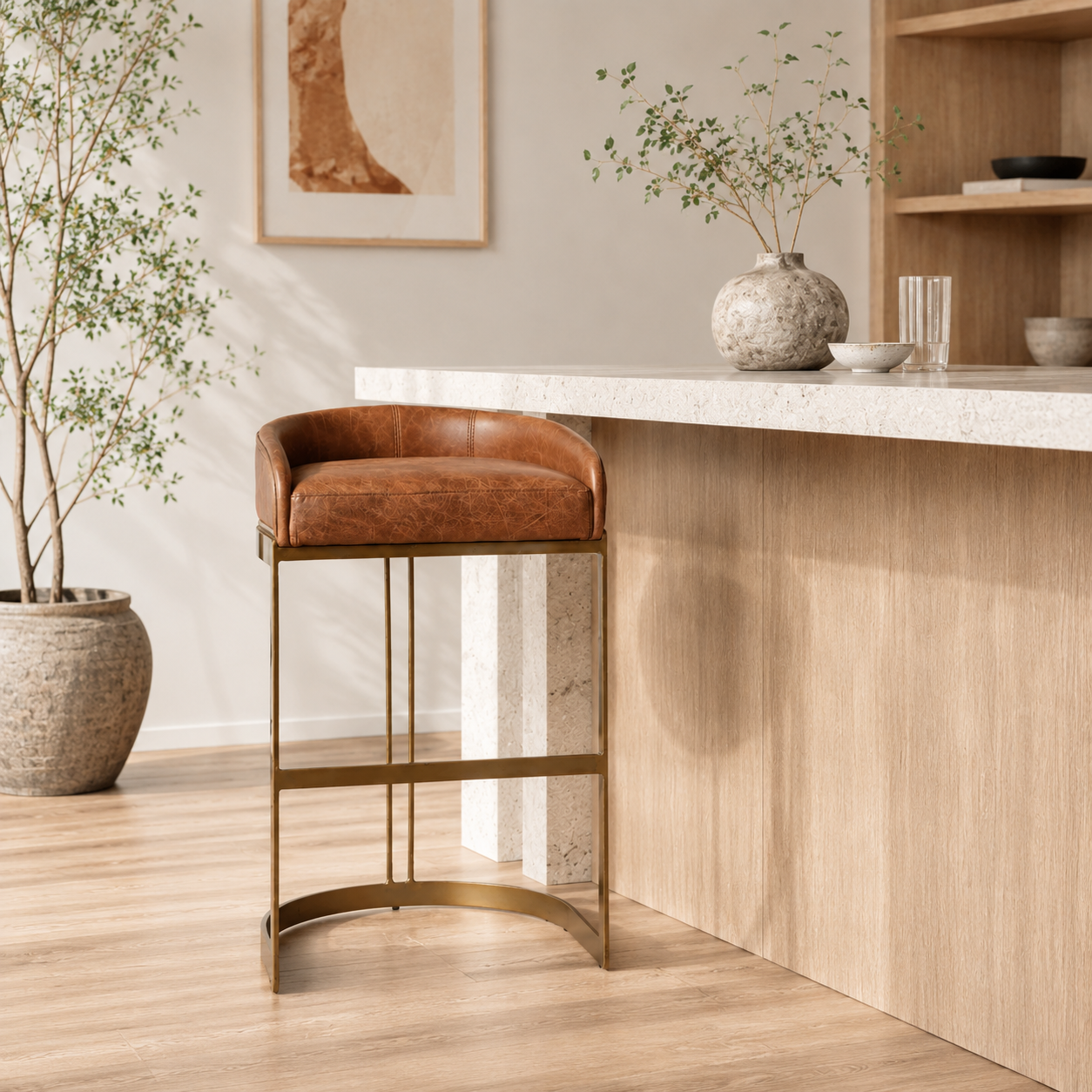 A modern bar stool featuring a curved brown leather seat cushion and backrest, supported by a slim gold-finished metal frame with a curved base, shown against a plain white background.