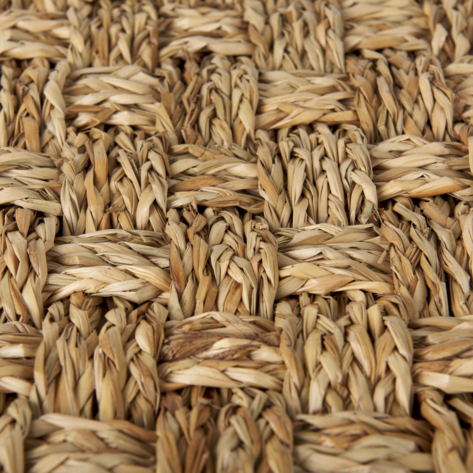 High-angled perspective showcasing the uniform square silhouette and handcrafted texture of the seagrass pouf