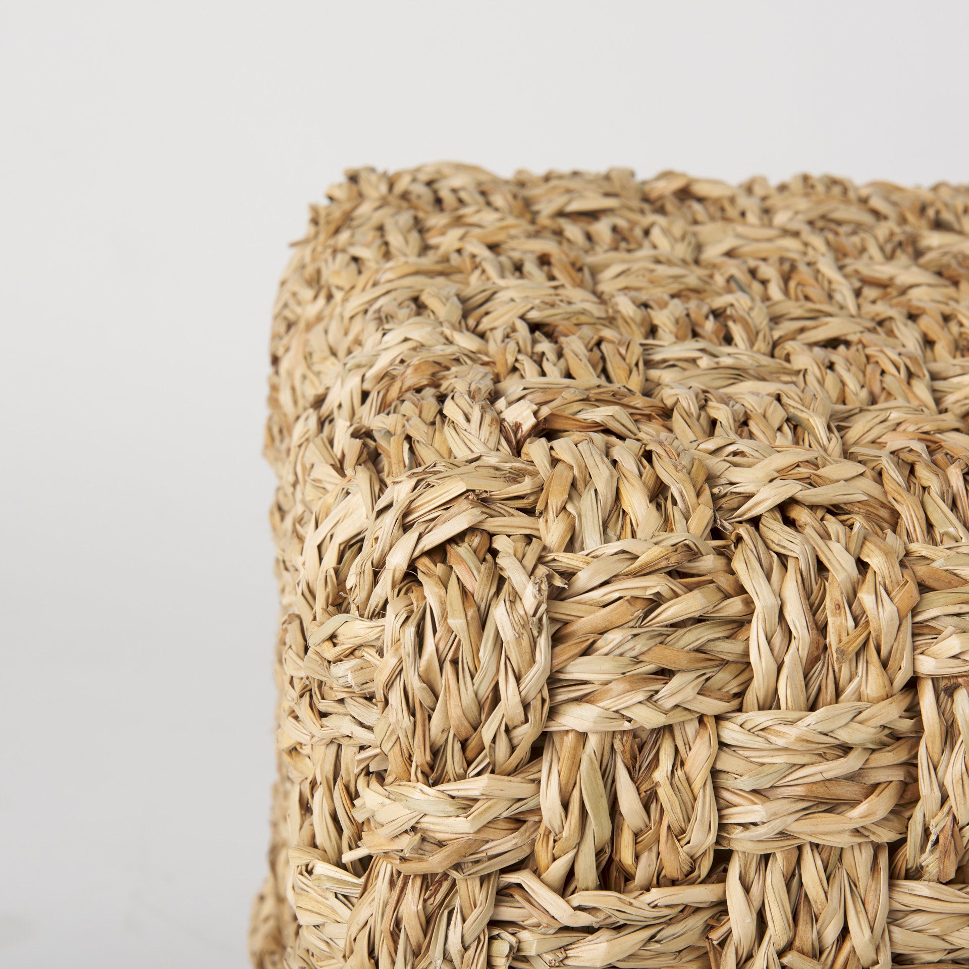High-angled perspective showcasing the uniform square silhouette and handcrafted texture of the seagrass pouf