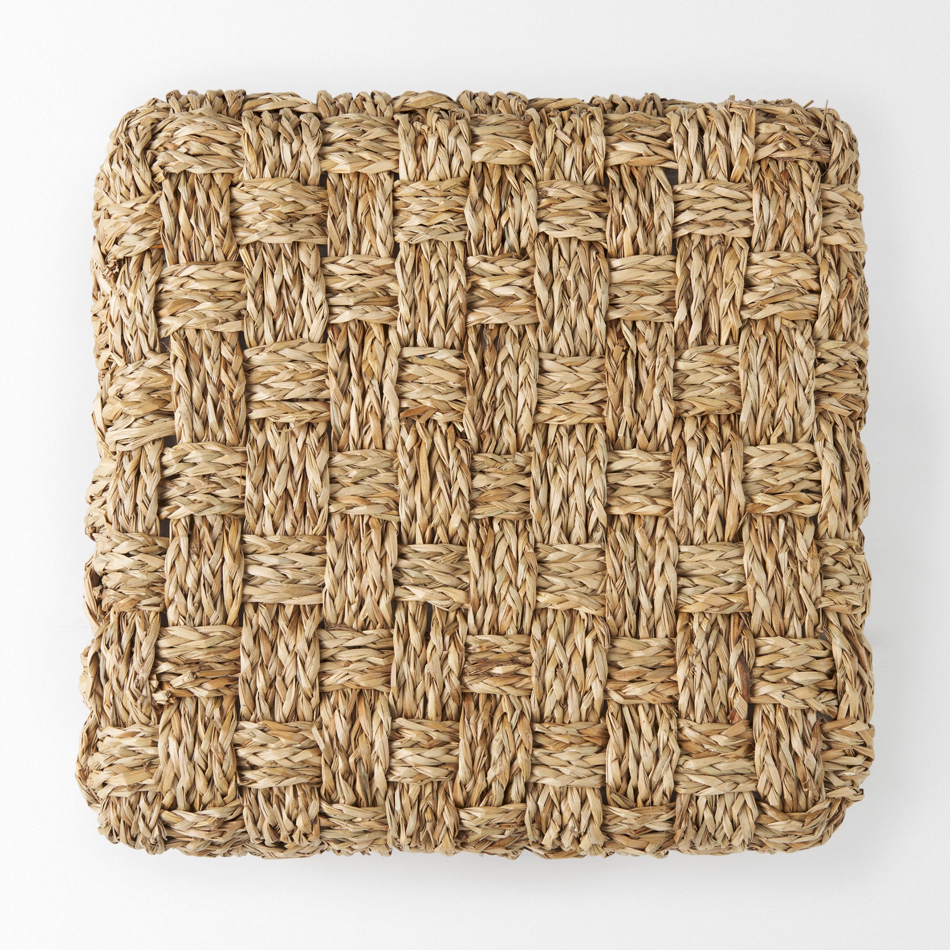 High-angled perspective showcasing the uniform square silhouette and handcrafted texture of the seagrass pouf