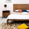 Studio lifestyle shot featuring the nightstand styled with a black lamp next to a coordinating solid wood bed frame