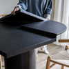 Action shot showing the unique folding mechanism as the round tabletop transitions into a larger square shape