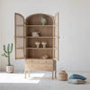 Lifestyle shot with open doors showcasing the cabinet interior styled with minimalist ceramic vases and books