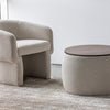 Lifestyle shot of the Ash bouclé ottoman styled alongside a matching cream swivel chair in a bright contemporary lounge