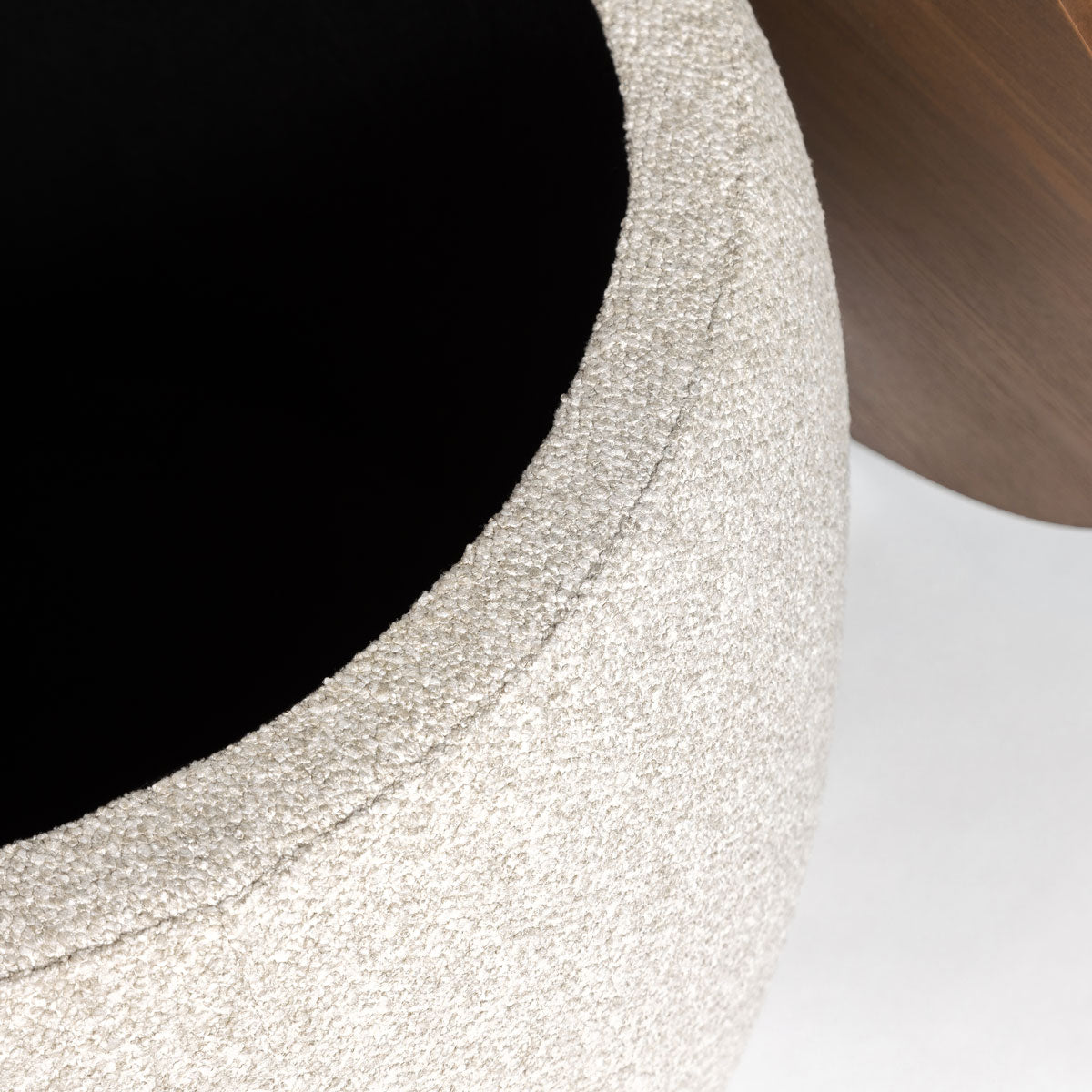 Front view of the Ash round storage ottoman featuring cream bouclé upholstery and a dark wood circular lid 