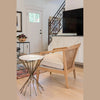 Lifestyle perspective demonstrating the table's scale next to a cane-back armchair in a modern home entryway