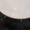 Close-up perspective showing the smooth beveled edge of the white marble top and the gold metal mounting brackets