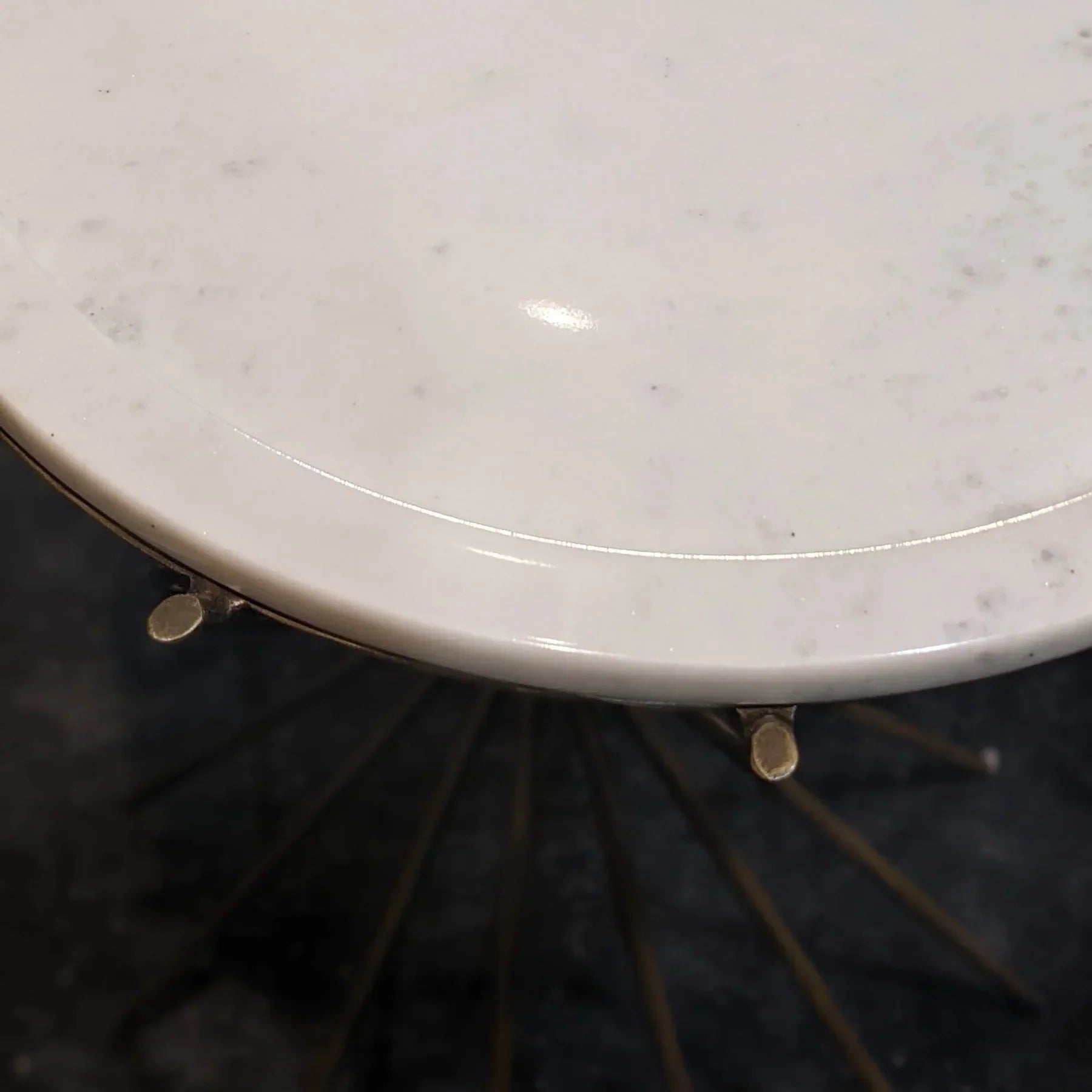 Close-up perspective showing the smooth beveled edge of the white marble top and the gold metal mounting brackets
