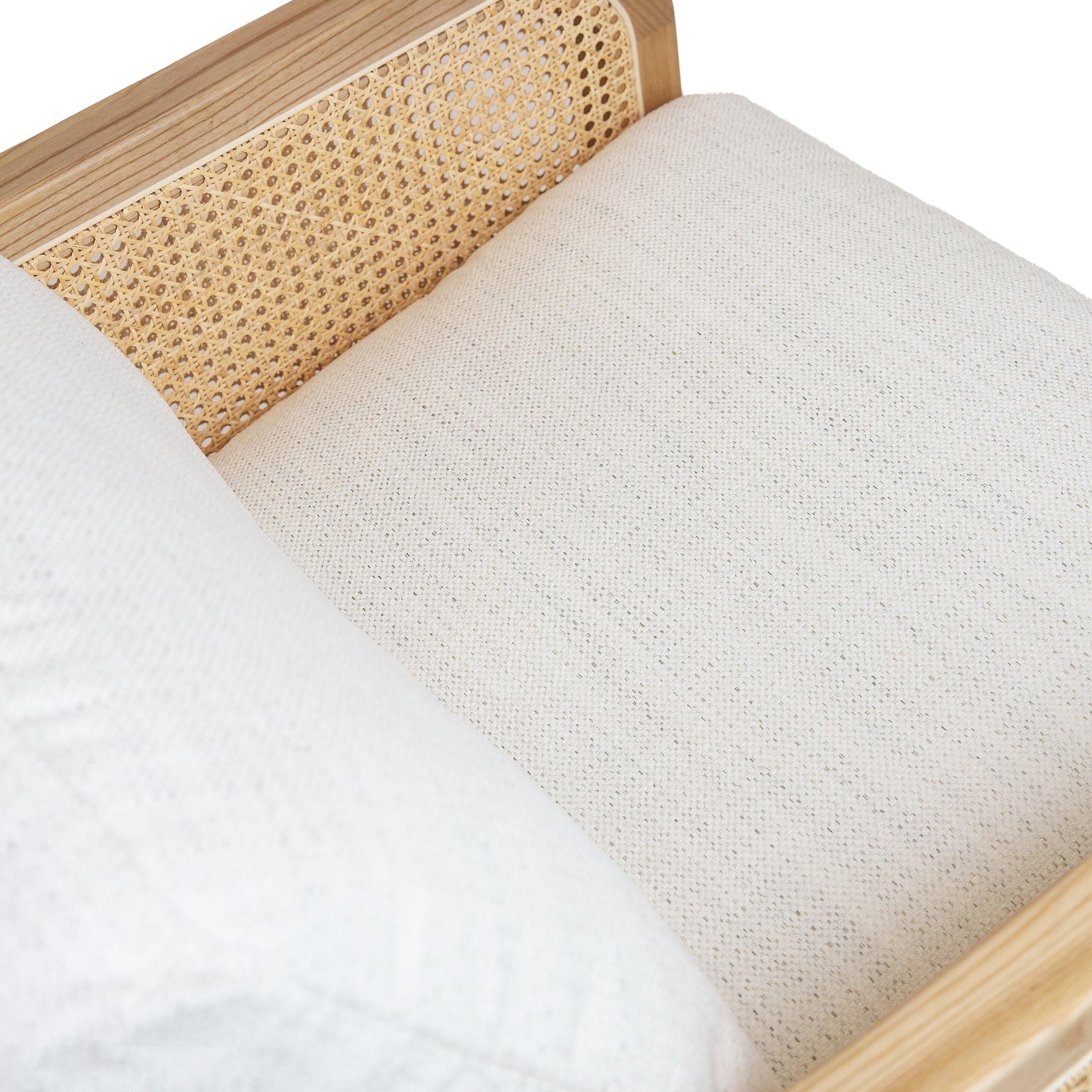 Low-angle detail of the woven cane texture and the light oak finish on the base of the chair.