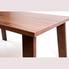 Close-up perspective highlighting the smooth walnut wood grain and clean rectangular edge of the tabletop