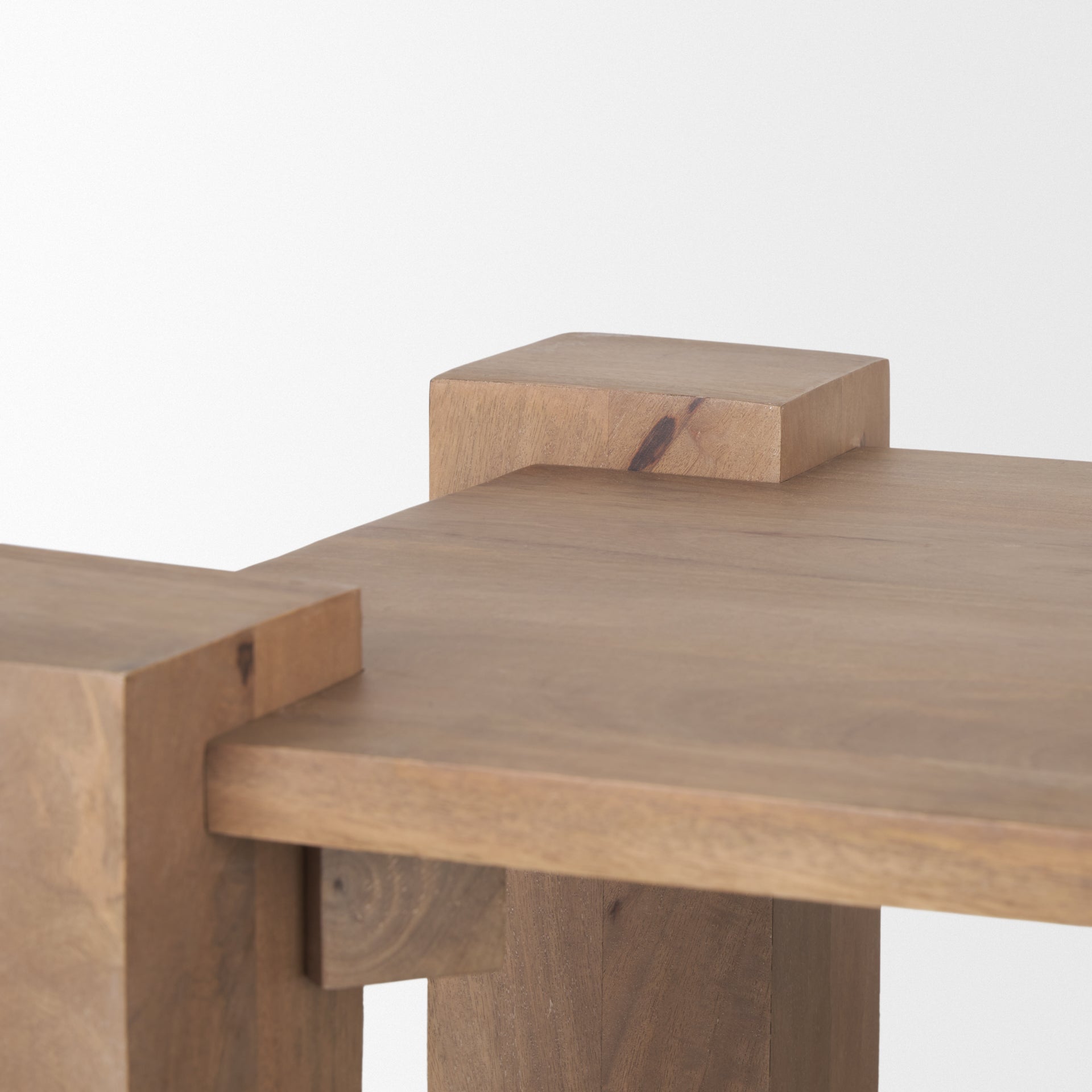 Close-up shot focusing on the natural wood grain and the unique corner construction of the light brown wooden accent table