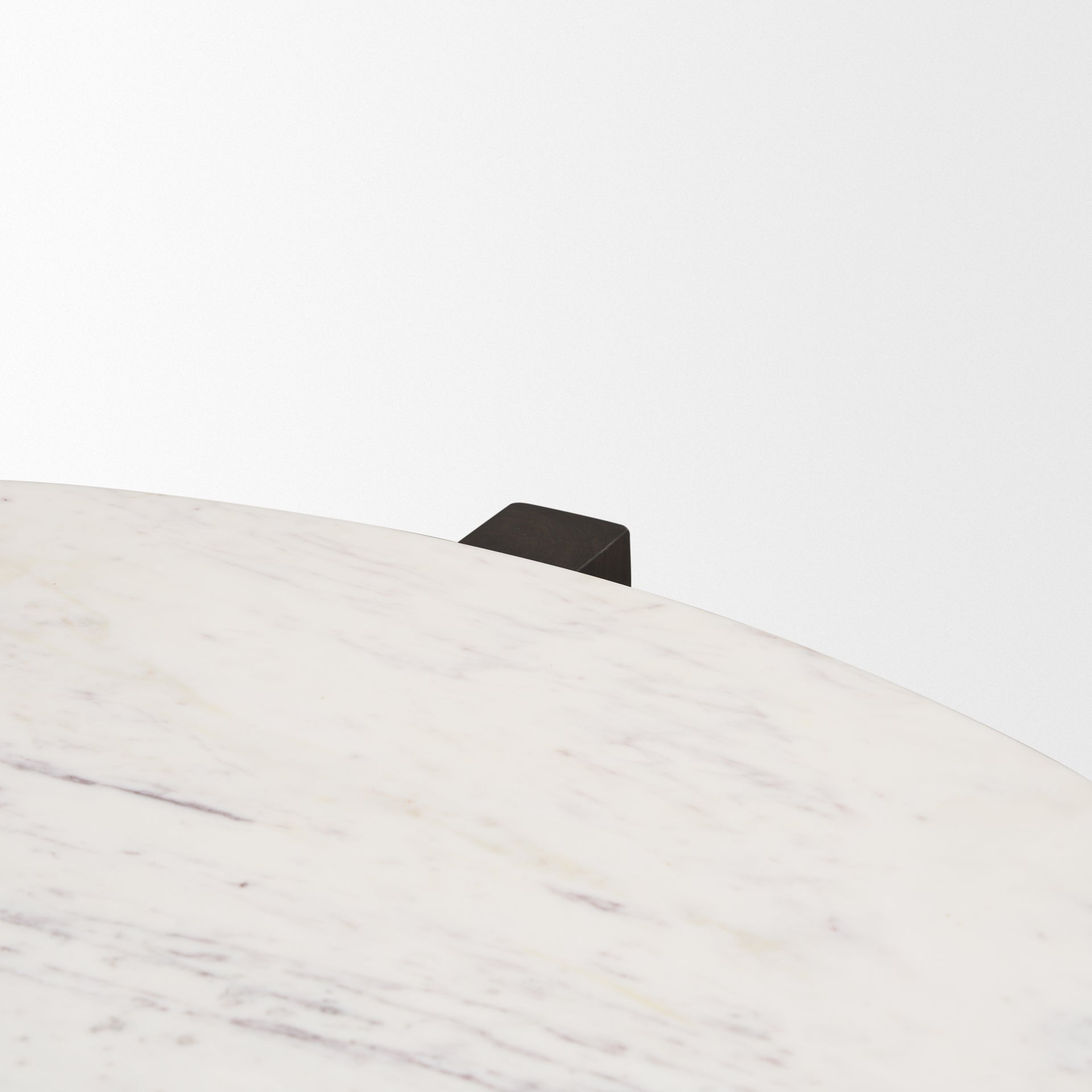 Close-up shot focusing on the seamless connection between the white marble top and the dark brown wood pedestal leg