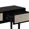 Perspective view with one drawer open revealing smooth internal storage and the contrast between black wood and light cane