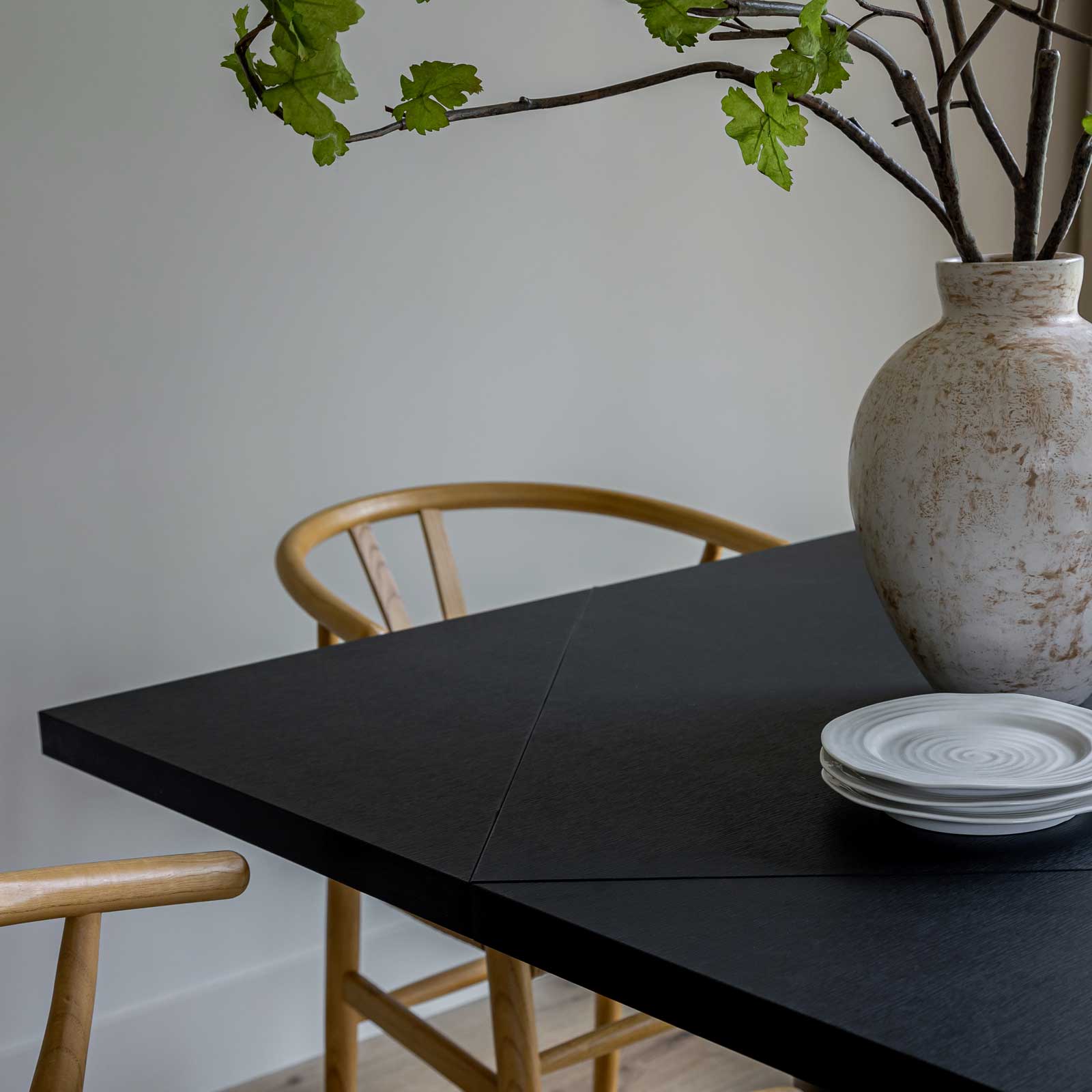 Front view of the Alter round dining table in a sleek black finish featuring a sturdy cylindrical pedestal base