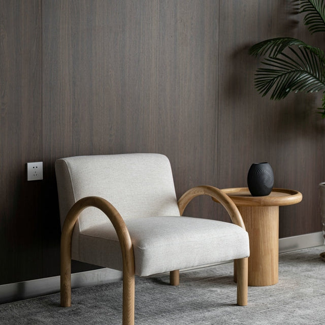 The Bo Accent Chair styled in a dark-walled minimalist room next to a matching oak side table.