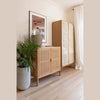 Vertical lifestyle shot of the sideboard positioned next to a tall matching cabinet and lush greenery