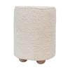 Front view of a cylindrical cream bouclé upholstered pouf featuring three rounded natural wood feet