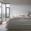 Wide-angle lifestyle shot showing the Justin bed as the central focal point in a bright, modern master suite
