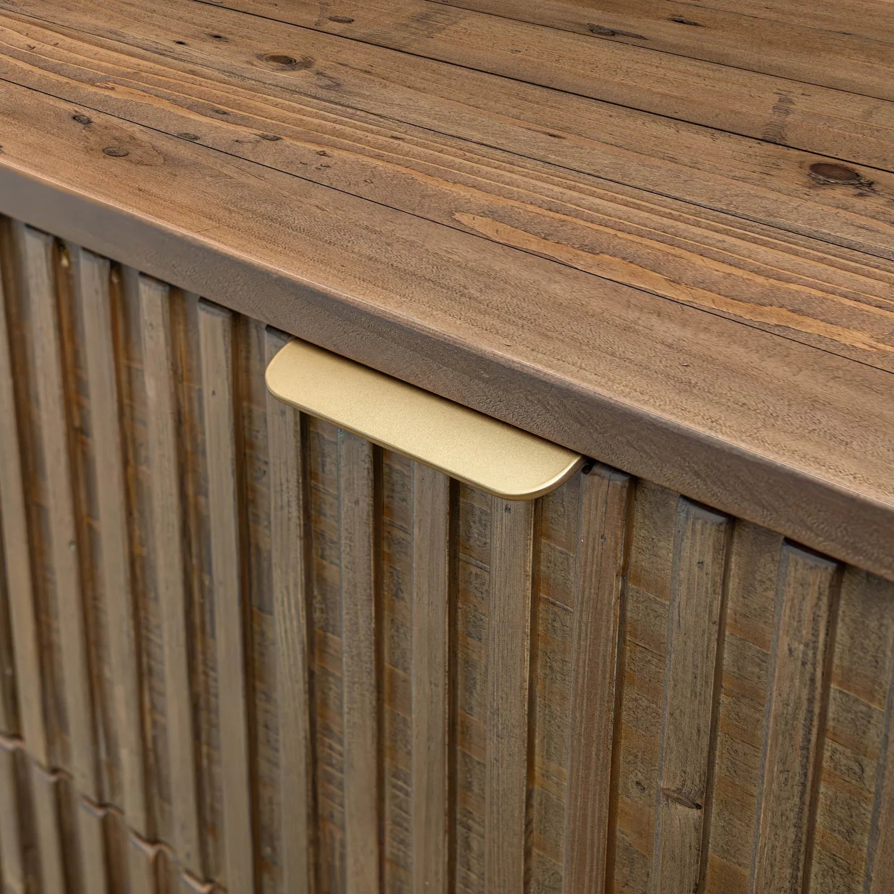 Front view of the Britanica 5-drawer chest featuring a warm rustic brown finish with vertical fluted wood textures and sleek gold metal handles