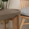 Close-up view highlighting the raised rim and porous texture of the brown stone tabletop and its seamless connection to the wooden leg