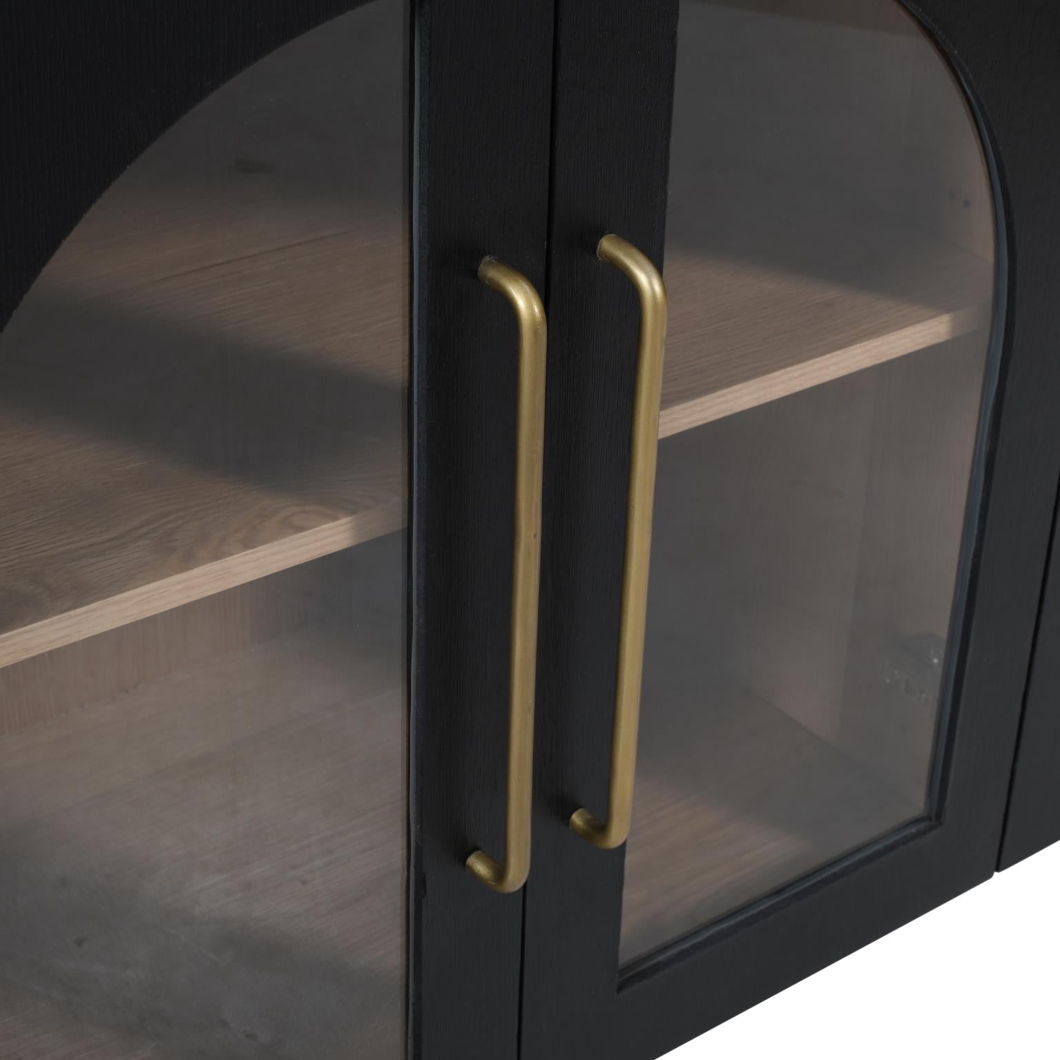 Macro shot highlighting the elegant brushed gold metal handles against the dark ebony oak arched glass doors