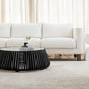 Lifestyle shot featuring the black slatted coffee table centered in a bright living room with a white sofa and cream rug