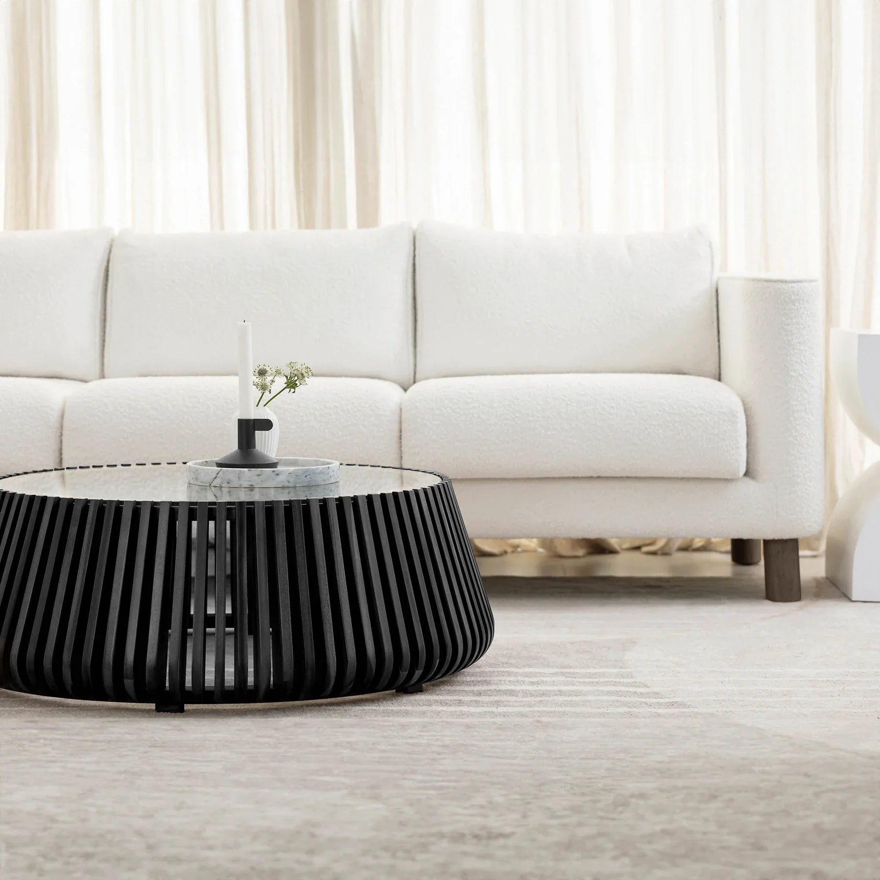 Front view of the Bungalow coffee table featuring a tapered cylindrical base made of black vertical wood slats and a clear glass inset top