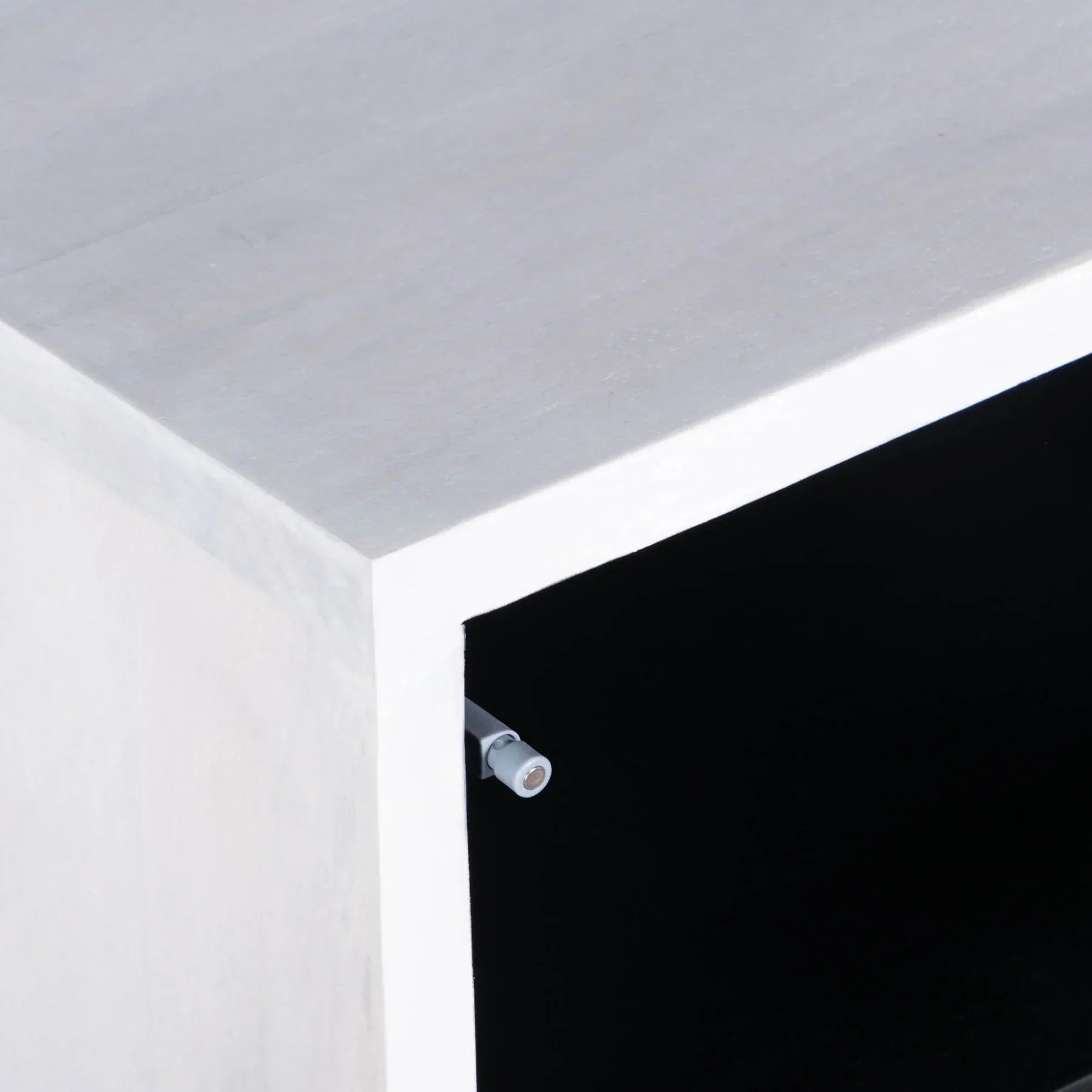 Three-quarter view of the Caged side table featuring a white-finished wooden body with a black-framed glass door and a minimalist metal box base