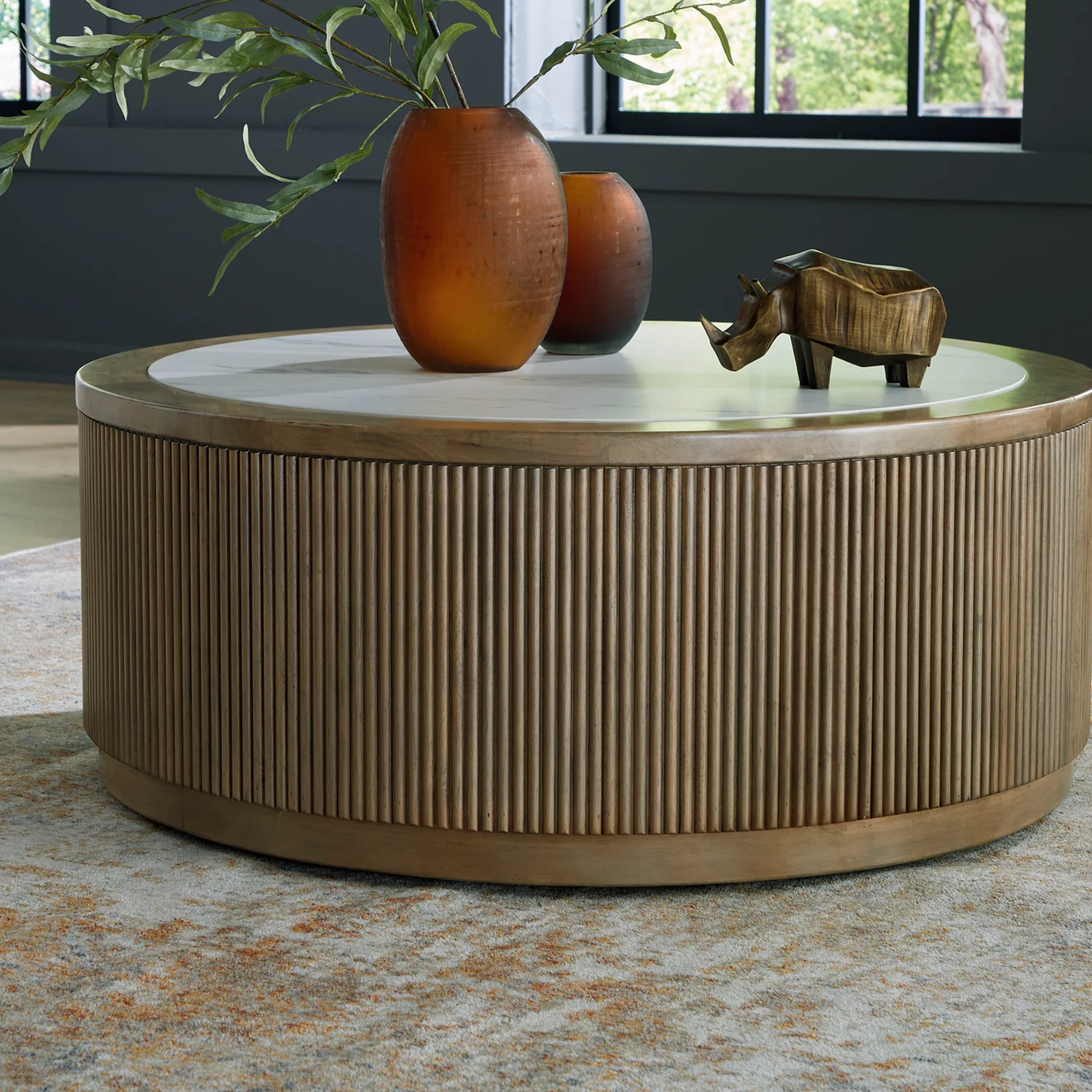 Lifestyle shot showing the Camdill cocktail table styled with dark orange vases in a modern living space