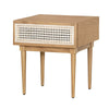 Three-quarter view of a mid-century modern side table in natural oak featuring a white woven cane drawer front and tapered legs