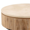 Three-quarter perspective highlighting the thick travertine surface and the smooth natural wood grain of the circular drum base