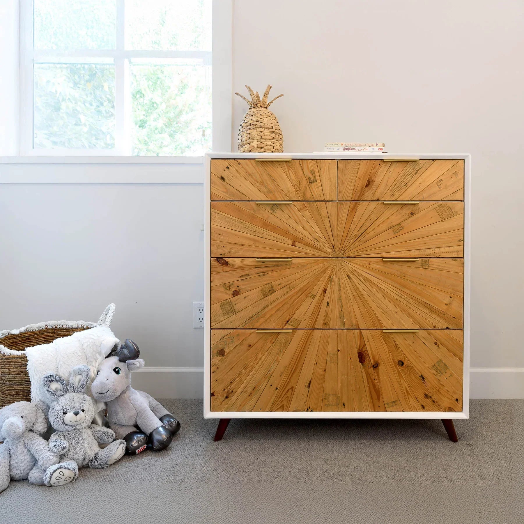 Studio lifestyle shot featuring the sunburst chest styled in a bright nursery setting with soft plush toys and neutral decor