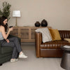 A person relaxing on the Channel camel brown leather sofa in a styled home