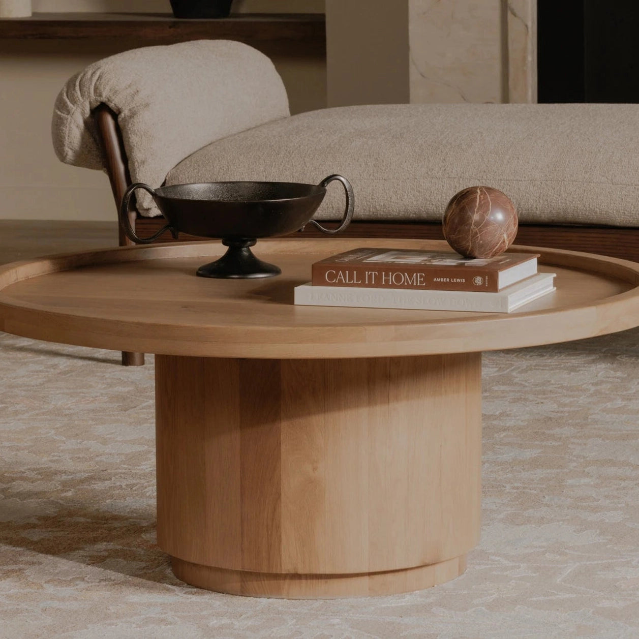 Lifestyle shot featuring the Cohen circular coffee table styled with decorative books and a marble bowl in a modern interior
