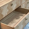 Macro detail shot of the upper facade focusing on the vertical fluted wood panels and black circular pull handles