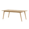 Three-quarter perspective view of the Colton large dining table featuring a natural oak finish and minimalist tapered wood legs