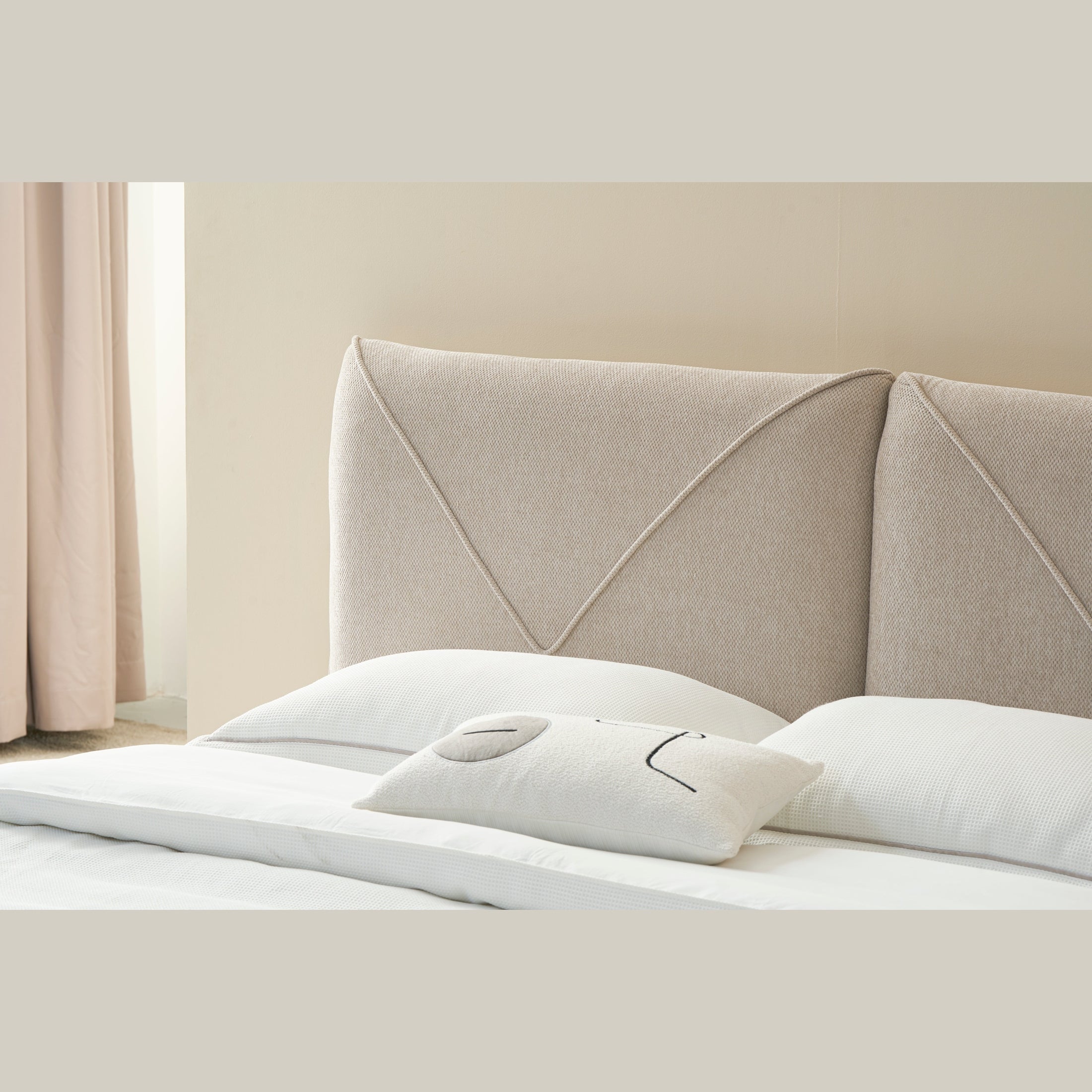 Front view of the Aici storage bed featuring a cream fabric finish and a unique V-shaped geometric stitched headboard
