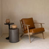 Wide lifestyle shot featuring the concrete table in a neutral-toned room paired with a leather chair and soft area rug