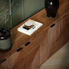 High-angle lifestyle shot of the sideboard surface styled with a ceramic vase and minimalist coffee table books