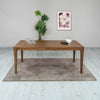 Real-home lifestyle shot featuring the dining table styled with a matching rug and neutral decor