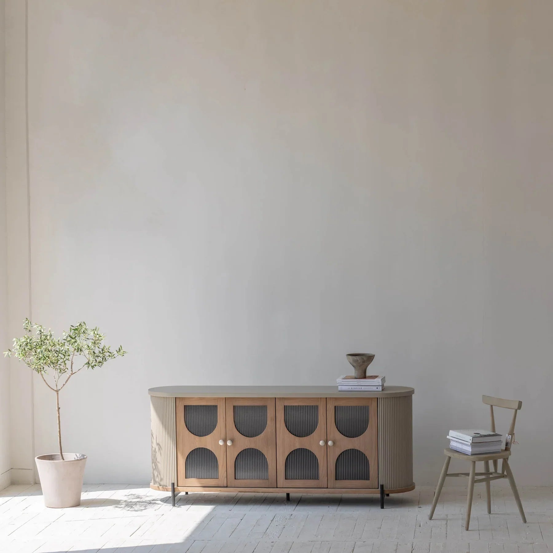 Wide-angle lifestyle shot showcasing the oval credenza as a statement piece in an airy modern interior