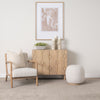 Lifestyle shot featuring the Heera cabinet styled with neutral decor and a framed art piece in a bright modern room