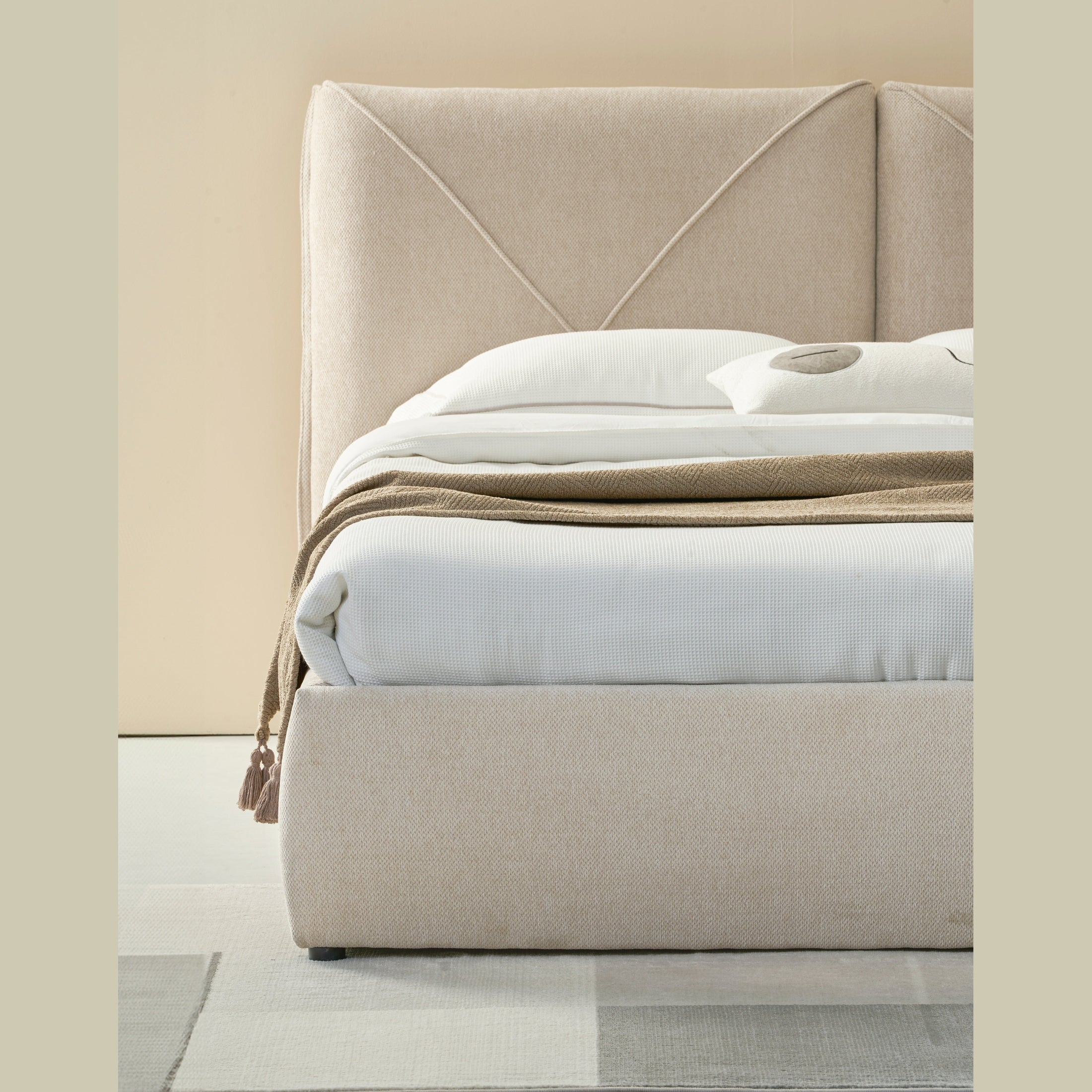 Front view of the Aici storage bed featuring a cream fabric finish and a unique V-shaped geometric stitched headboard