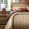 Perspective detail shot of the headboard styled with warm, patterned pillows and a modern bedside lamp
